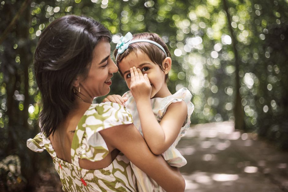 A joyful moment between mother and daughter in a sunlit park, capturing love and happiness.