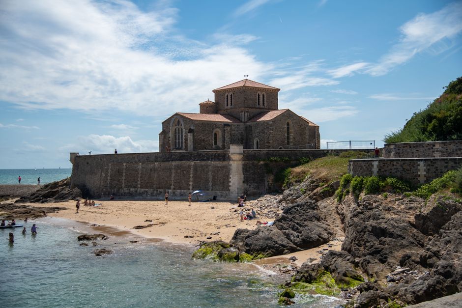 Scenic view of Prieure Saint-Nicolas church by the beach in France, under a blue sky.
