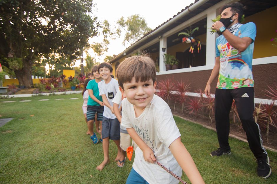Children enjoy a tug-of-war game outdoors, celebrating teamwork and fun in a garden.