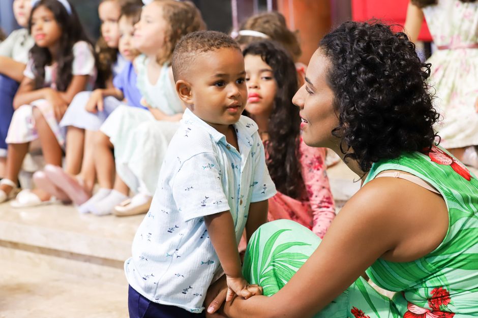 A mother lovingly engages with her child at a lively indoor gathering.