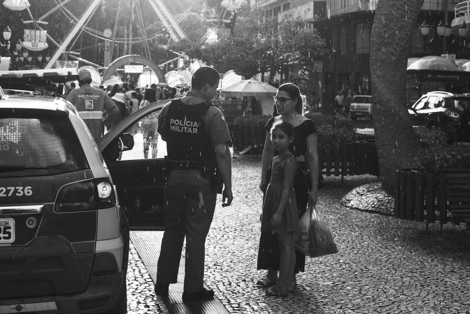 Black and white image of a police officer interacting with a family on a rainy street.