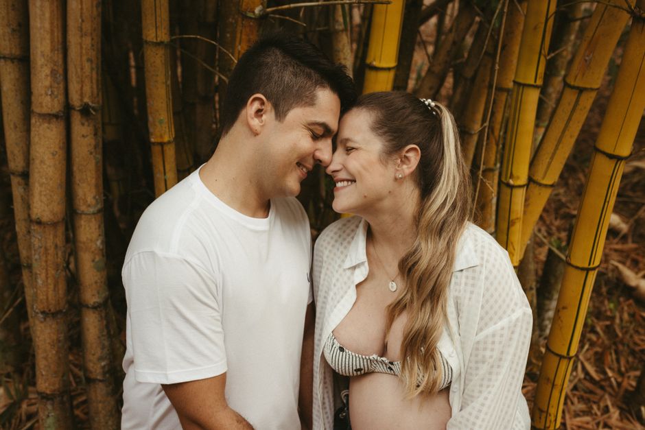Happy couple embracing in a lush bamboo forest, celebrating pregnancy and love.