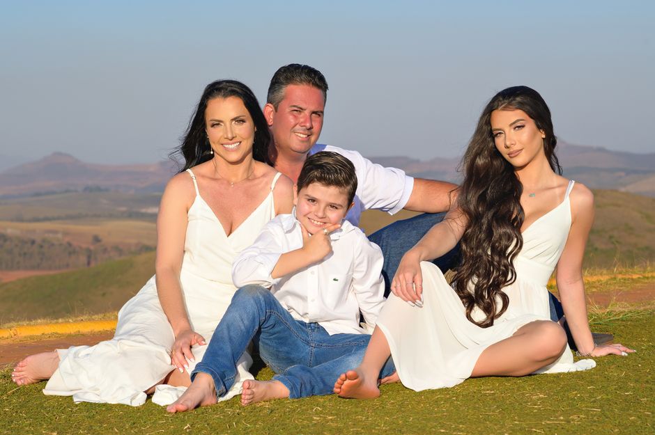 A joyous family sitting together in a sunny countryside field, dressed in white.