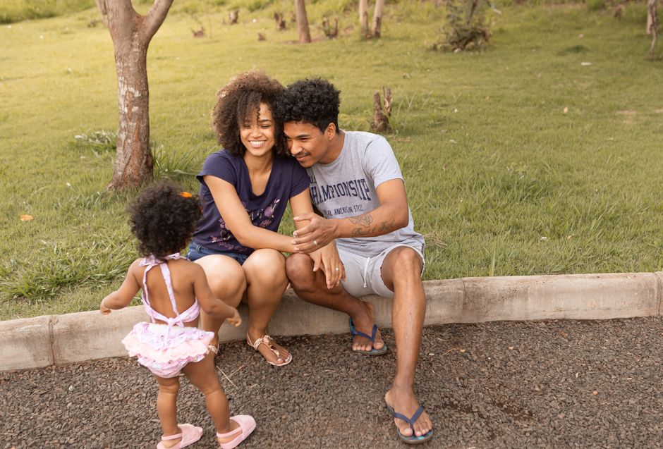 Happy family enjoying time together in a sunny park with their toddler daughter.