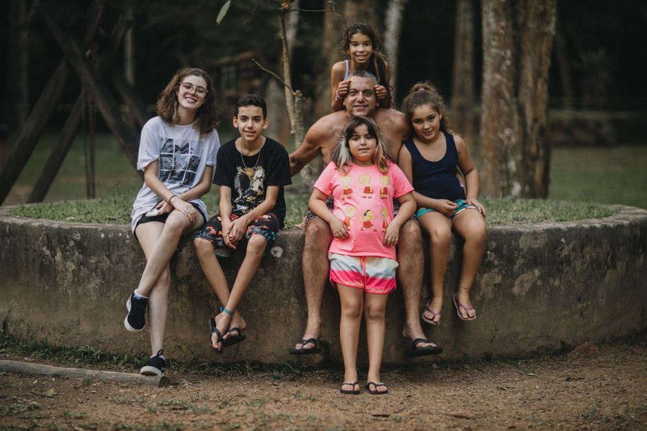 Group of people sitting on a stone ledge in a forest, smiling and enjoying nature.