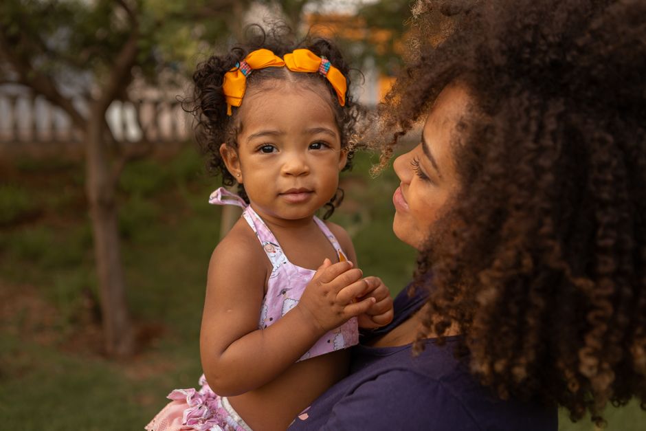 Charming portrait of a mother holding her daughter outdoors, showcasing love and connection.
