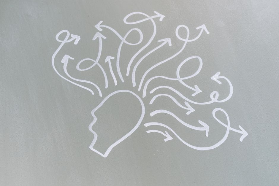 Chalk drawing of a head with swirling arrows represents mental activity and thought process.