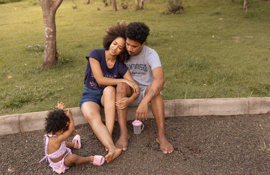 A family enjoys bonding time sitting together on a sunny day in a park.