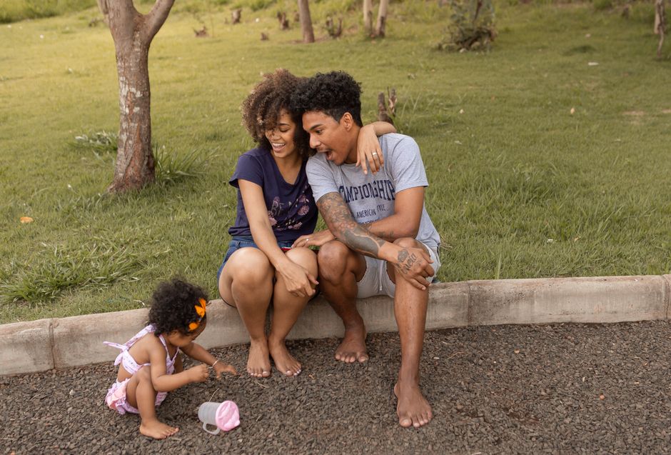 A joyful family moment with parents and child in a park setting.