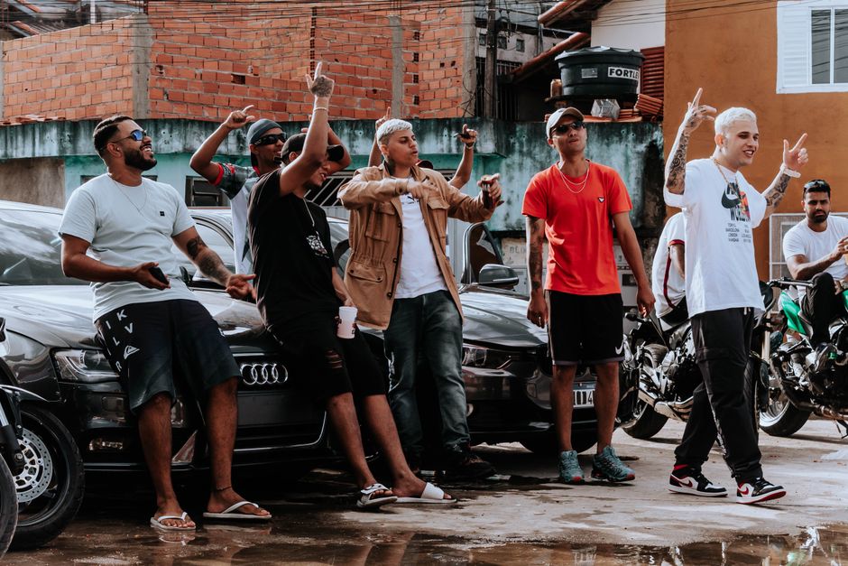 Young men pose with cars and motorcycles in an urban setting, capturing street culture.