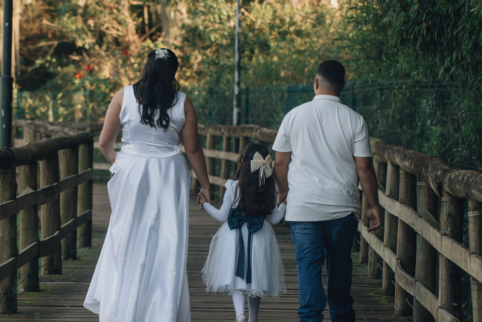 A family walking on a wooden bridge in nature, captured in an outdoor setting.