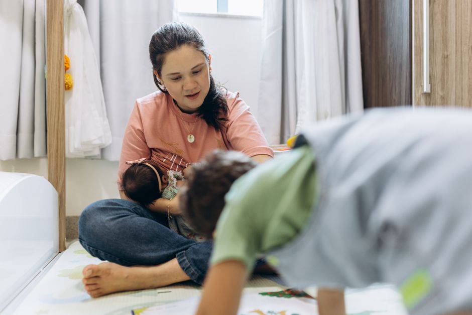 A mother enjoying playtime with her children at home in a cozy room setting.