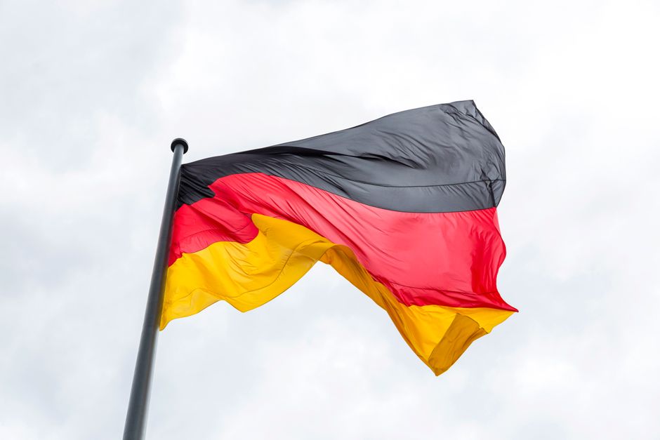 Vibrant German flag flying against a backdrop of a cloudy sky, symbolizing national pride.