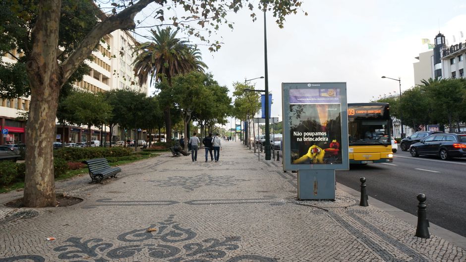 A lively street in Lisbon, Portugal with people walking and a city bus passing by.