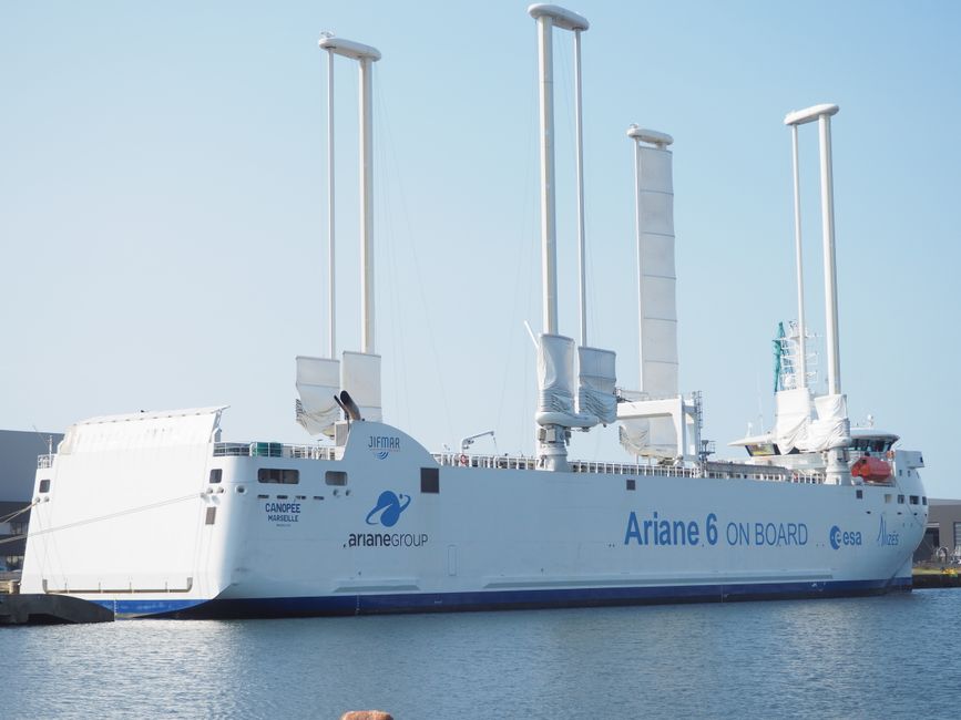 Ariane 6 cargo ship with high-tech sails docked at port during the day.